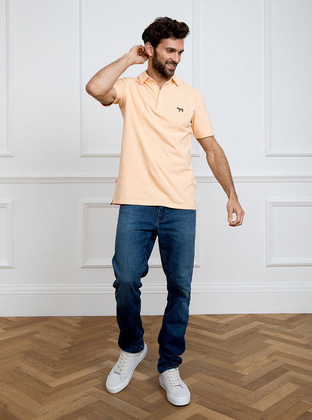 Man wearing peach coloured polo shirt in 100% cotton with Newmarket 875 horse logo embroidered on the front.